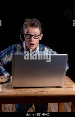 Boy with shirt and glasses headset doing e learning on laptop Stock Photo