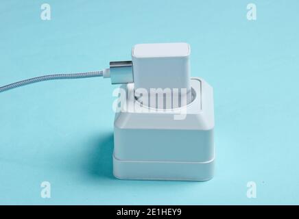 Charger plugged into power outlet on blue background Stock Photo