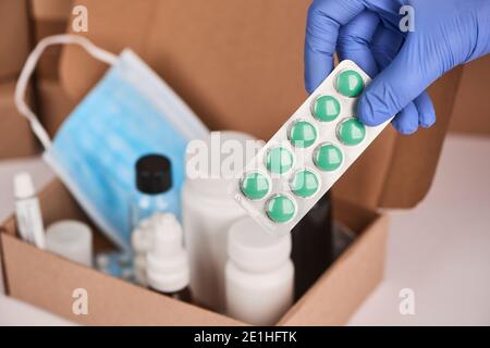 Close-up on a hand in glove holding a blister of pills Stock Photo