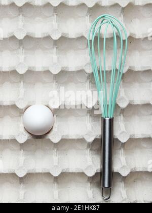 Whisk and eggs in tray. Top view, closeup Stock Photo