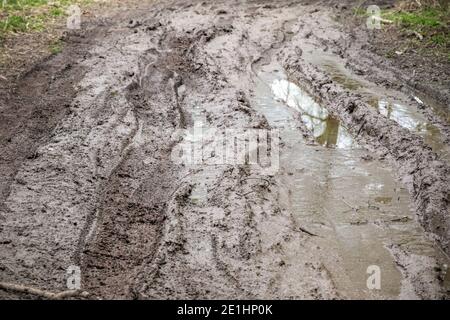 Extremely muddy trail with messy tire tracks after rainfall next to River Cole in Whelford, England Stock Photo