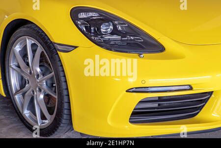 Bangkok, Thailand - 06 Jan 2021 : Close-up of Car Headlights and Car Wheel of Yellow Porsche Sports Car parked in the parking lot. Selective focus. Stock Photo