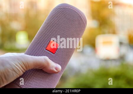 A man holding a Portable pink wireless speaker in his hand. Close-up, selective focus Stock Photo