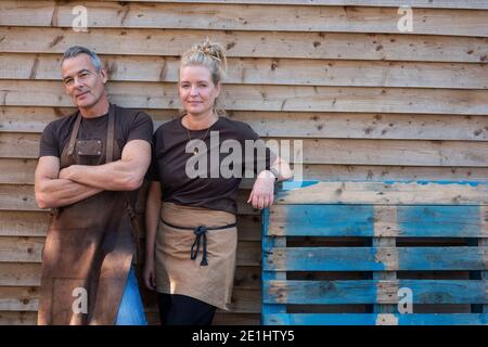 Man and woman in aprons, colleagues taking a break from work, laughing Stock Photo