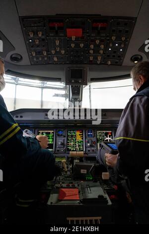 Kyiv, Ukraine - November 25, 2020: Embraer aircraft cockpit. Pilots in medical masks. Technicians diagnose, repair and service the aircraft. Workers w Stock Photo