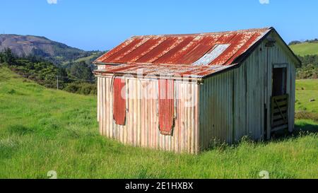 An old, rustic wood and corrugated iron barn on a farm in New Zealand hill country Stock Photo