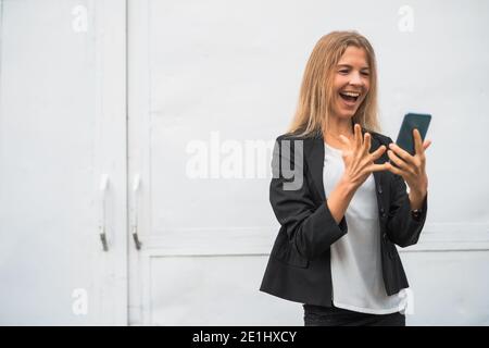 Outdoor portrait of ecstatic modern businesswoman who is joyful. She is holding smartphone. Stock Photo