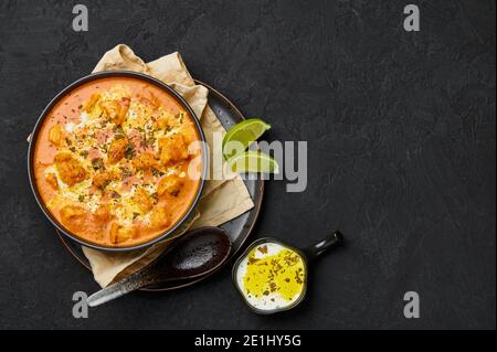 Murgh Makhani or Butter Chicken in black bowl on dark slate table top. Indian Cuisine dish with chicken meat and creamy masala. Asian food and meal. C Stock Photo