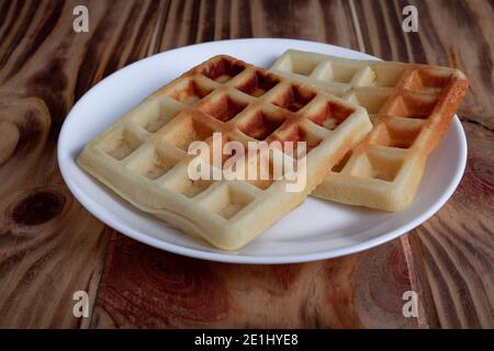 Sweet Belgian Viennese waffles without additives on a plate on wooden table for breakfast Stock Photo