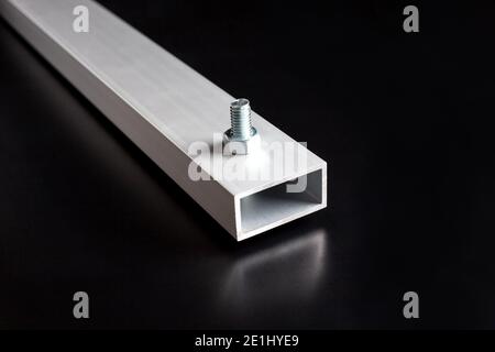 Fragment of a aluminum metal tube construction with bolt and nut on dark surface background Stock Photo