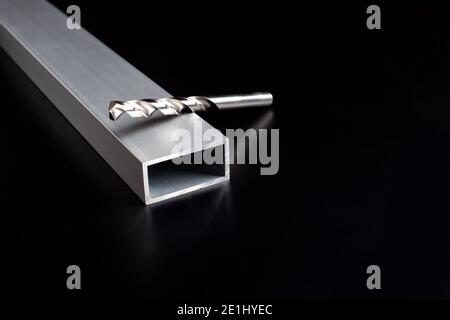 Drills from an electric drill lie on a aluminum steel tube on dark surface Stock Photo