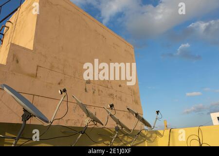A row of dish antennas fixed on the wall of the roof top and pointing  in the same direction Stock Photo