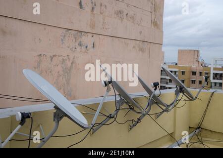 A row of dish antennas fixed on the wall of the roof top and pointing  in the same direction Stock Photo