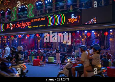 Walking street Bui Vien during lockdown. People are relaxing on the open terrace in the night restaurant. Vietnam, Ho Chi Minh: 2020-12-04 Stock Photo