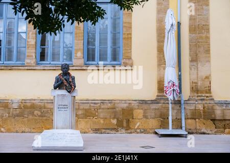 Nicosia, Cyprus - December 9, 2020: Contrasting view of the bust of Ourania Kokkinou next to an umbrella in front of Faneromeni School, Nicosia old ci Stock Photo