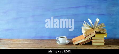 Stack of books,an opend book and cup of coffee.Education,reading,literature, home office, panoramic with large copy space Stock Photo