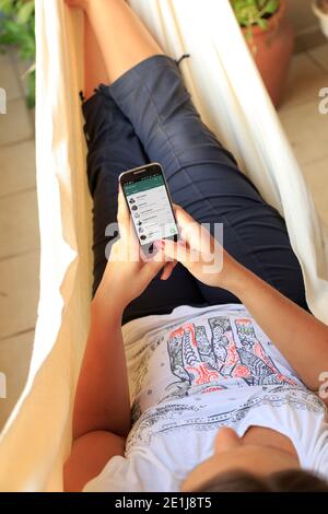 ROSARIO, ARGENTINA - JANUARY 19, 2017: Girl in a hammock with a smartphone in her hands and Whatsapp´s contact list on screen. Young woman, millennial Stock Photo