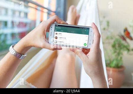 ROSARIO, ARGENTINA - JANUARY 19, 2017: Girl in a hammock with a smartphone in her hands and Whatsapp´s contact list on screen. Young woman, millennial Stock Photo