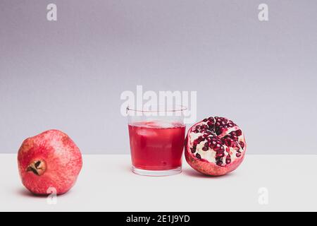 Minimalistic still life with pomegranate fruit and pomegranate juice in a glass Stock Photo