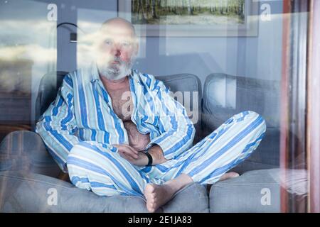 Elderly man wearing pajamas in isolation because of Covid. Stock Photo