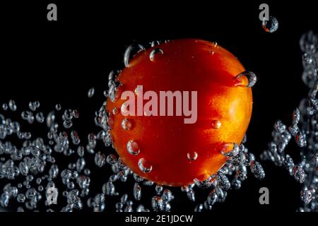 fresh red tomato with water bubbles. the concept of freshness of fruit in water. underwater vegetable photo with isolated black background Stock Photo