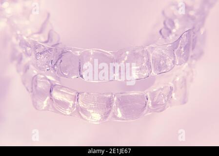 Invisible aligner teeth retainers on a pink background Stock Photo