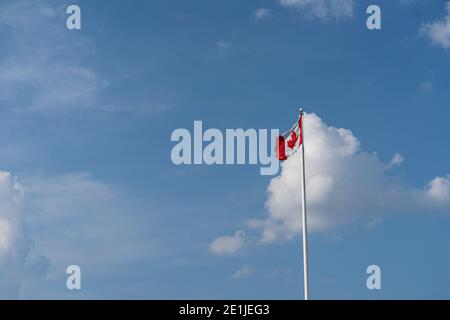 Canada Flag against blue sky with cloud. Seen from far Stock Photo