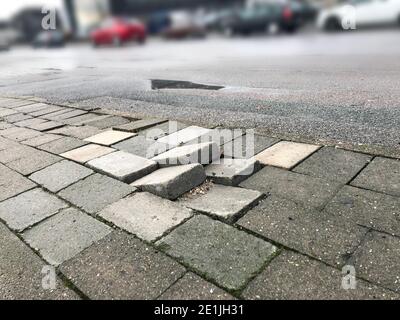Sidewalk pavement tiles for pedestrians are uneven due to lack of maintenance can cause danger for pedestrians and traffic Stock Photo