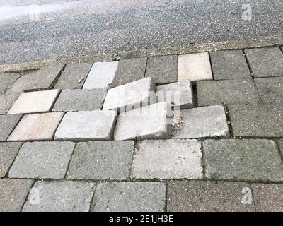 Sidewalk pavement tiles for pedestrians are uneven due to lack of maintenance can cause danger for pedestrians and traffic Stock Photo
