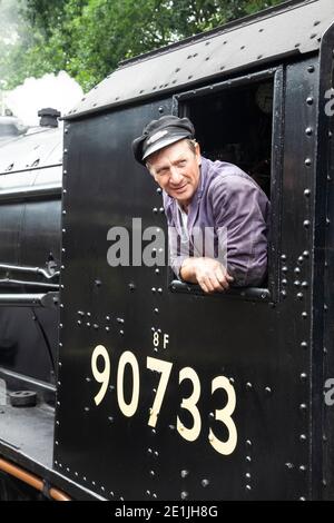 An engine driver or engineer in the cab of a steam train locomotive number 90733 2-8-0 on the Keighley & Worth Valley heritage line in Yorkshire Stock Photo