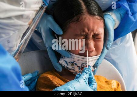 Shah Alam, Malaysia. 07th Jan, 2021. A medical worker wearing a personal protective equipment (PPE) takes a nasal swab sample from a child during the Covid-19 screening test in Shah Alam. Malaysia has recorded 3,027 new cases of coronavirus today bringing the total to 128, 465 cases. Selangor has conducted targeted community screening on residents around Sri Muda, Shah Alam following a spike of Covid-19 positive cases. Credit: SOPA Images Limited/Alamy Live News Stock Photo