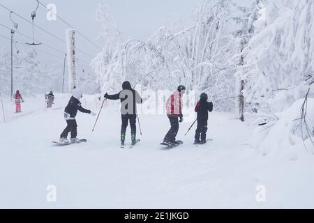 Perm Krai, Russia - January 02, 2021: teenage skiers and snowboarders are going to slide down a mountain along a forest trail in frosty weather Stock Photo