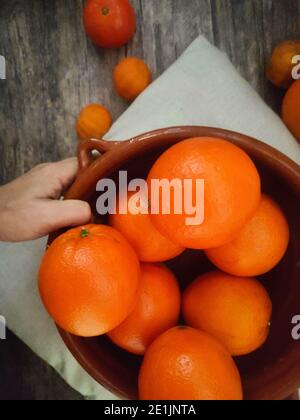 Oranges, mandarin oranges, tangerines, all citrus fruit in bowl and on a rural kitchen table Stock Photo