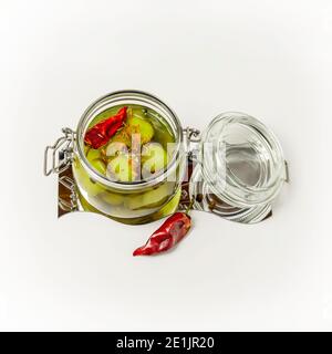 Pickled cucumbers with spices and pepper in an open glass jar on a white background. Fermented vegetables. Food preservation. Square orientation Stock Photo
