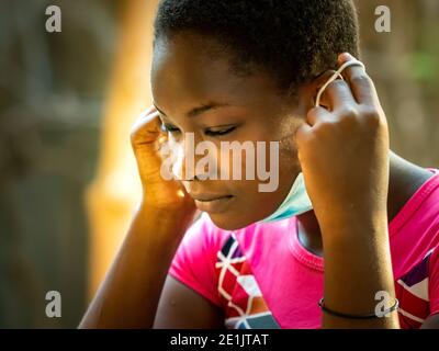 MBOUR, SENEGAL - DECEMBER Circa, 2020. concept showing of improper way of using face masks during coronavirus or covid-19 crisis - young black woman w Stock Photo