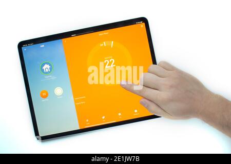 Calgary, Alberta, Canada. Jan 03 2021. A person using an iPad Pro using the Nest smart thermostat application turning the heat on. Stock Photo