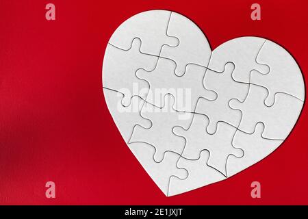 Heart-shaped jigsaw puzzle on color background. Puzzle heart on wooden background. A missing piece of the heart puzzle. Heart shape jigsaw puzzle. Puz Stock Photo