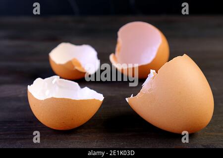 Closeup cracked eggshells isolated on dark brown wooden table Stock Photo