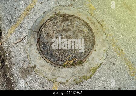 A metal storm drain manhole on concrete in Athens Stock Photo