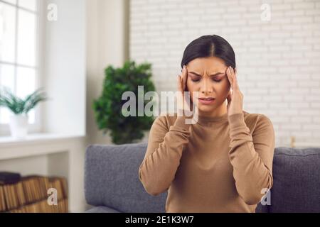 Tired stressed young woman touching her temples, suffering from headache or migraine Stock Photo
