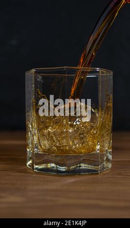 Whiskey drinks on wood with ice cubes and splash. Stock Photo