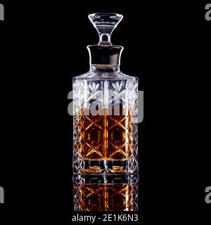 Straight sided glass decanter containing whisky, brandy or rum on black background Stock Photo