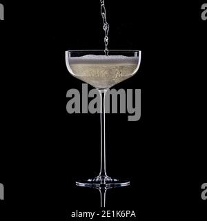 Champagne or Prosecco pouring into tall stemmed champagne coupe on black background Stock Photo