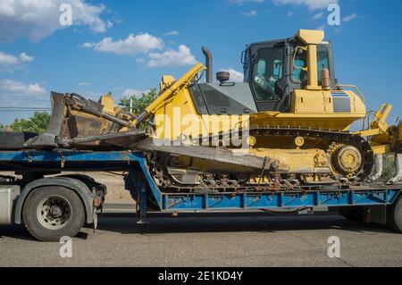 Heavy-duty truck carrying bulldozer equipped with multishank ripper. Heavy duty transports Stock Photo