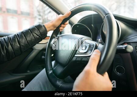 Man driving car. Close up of driver hands on the steering wheel Stock Photo