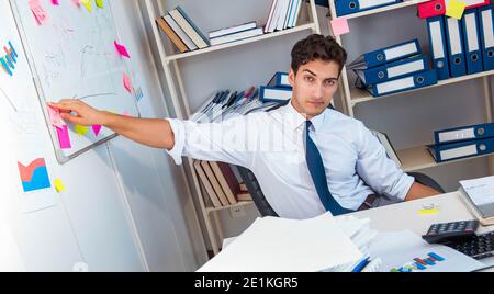 Businessman working in the office with piles of books and papers doing paperwork Stock Photo