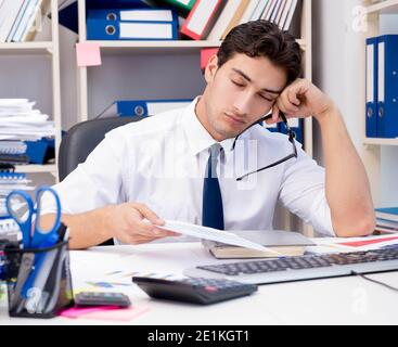 Businessman working in the office with piles of books and papers doing paperwork Stock Photo