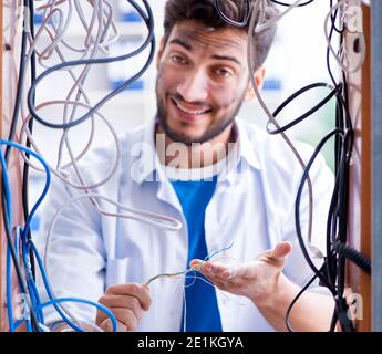 The electrician trying to untangle wires in repair concept Stock Photo