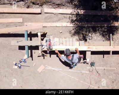 Overhead view of a carpenter working outside using a circular saw to trim wood Stock Photo
