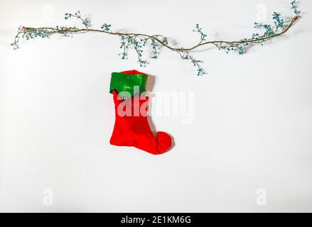 Christmas stocking hanging on a white wall with decoration. Copy space Stock Photo